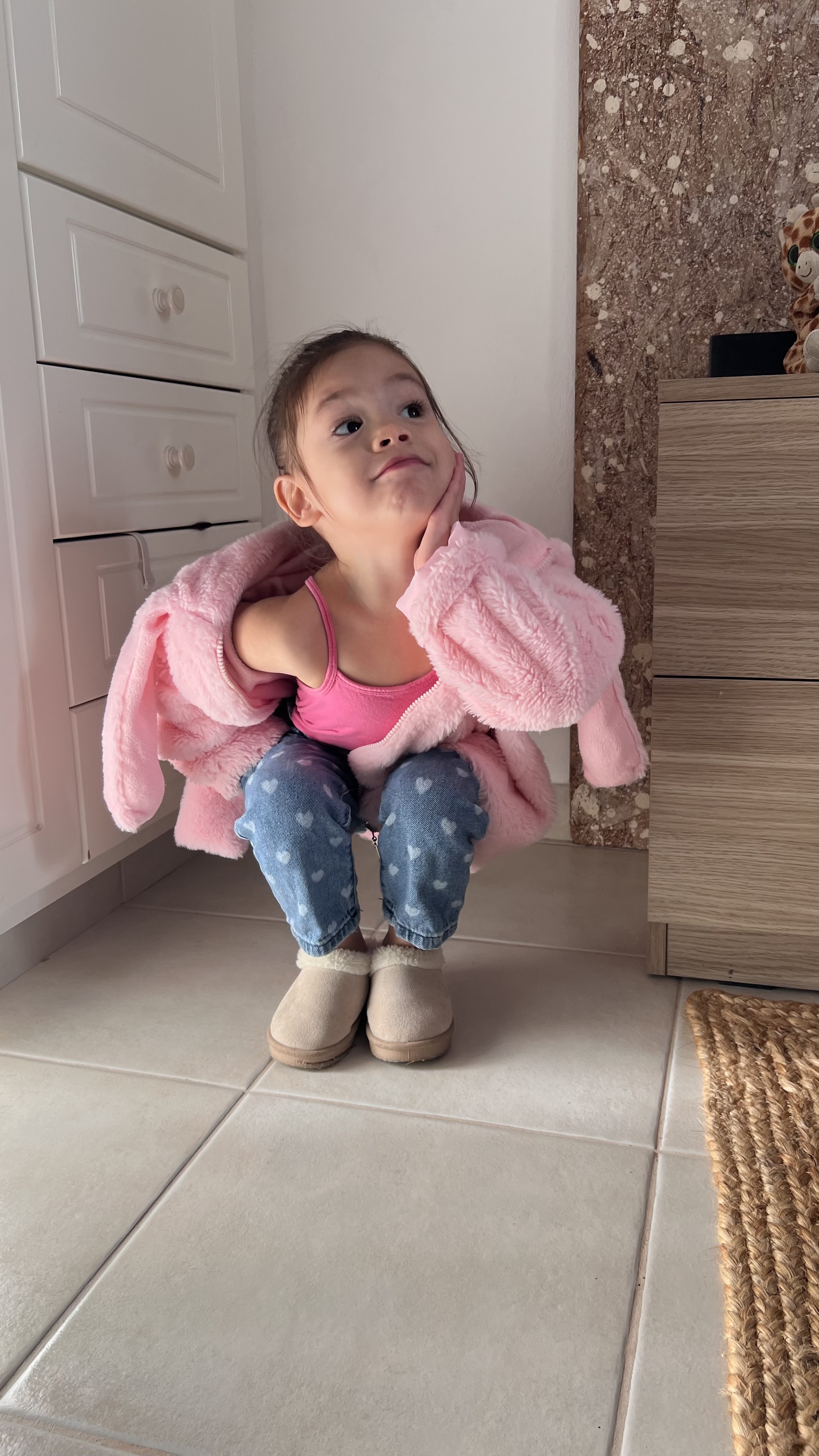 Kiara crouching with her hand against her cheek and looking upwards.